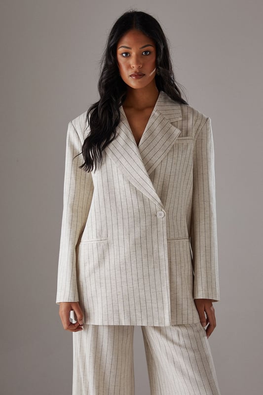 Boxy fit blazer with classic pinstripe pattern for a contemporary twist on tailoring
        Single button fastening creates a clean, streamlined silhouette
        Notched lapel collar adds traditional tailoring detail
        Long sleeves with structured shoulders for a confident, defined shape
        Linen-look fabric offers a textured finish with natural drape
    
    This Warehouse blazer redefines casual sophistication with its relaxed boxy silhouette and distinctive pinstripe pattern. The linen-look fabric creates a textured appearance whilst maintaining a fluid drape that moves beautifully with the body. Style as seen with the matching wide-leg trousers for a coordinated suit that conveys confidence without trying too hard. For daytime engagements, pair with a simple t-shirt and trainers for an effortlessly cool look. When evening calls, swap for a silk camisole and statement jewellery. This versatile piece transitions seamlessly from family gatherings to casual office environments, and even weekend brunches. The relaxed structure makes it ideal for layering over lightweight knits during transitional seasons, whilst the timeless pinstripe pattern ensures this blazer will remain a wardrobe staple for years to come.
