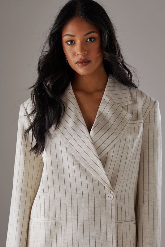 Boxy fit blazer with classic pinstripe pattern for a contemporary twist on tailoring
        Single button fastening creates a clean, streamlined silhouette
        Notched lapel collar adds traditional tailoring detail
        Long sleeves with structured shoulders for a confident, defined shape
        Linen-look fabric offers a textured finish with natural drape
    
    This Warehouse blazer redefines casual sophistication with its relaxed boxy silhouette and distinctive pinstripe pattern. The linen-look fabric creates a textured appearance whilst maintaining a fluid drape that moves beautifully with the body. Style as seen with the matching wide-leg trousers for a coordinated suit that conveys confidence without trying too hard. For daytime engagements, pair with a simple t-shirt and trainers for an effortlessly cool look. When evening calls, swap for a silk camisole and statement jewellery. This versatile piece transitions seamlessly from family gatherings to casual office environments, and even weekend brunches. The relaxed structure makes it ideal for layering over lightweight knits during transitional seasons, whilst the timeless pinstripe pattern ensures this blazer will remain a wardrobe staple for years to come.