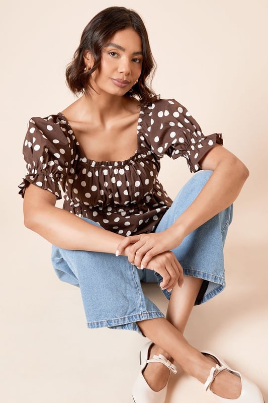 Charming square neckline with delicate gathering detail for a feminine touch
        Playful puff sleeves with elasticated cuffs for a flattering silhouette
        Lightweight cotton poplin fabric ensures breathable comfort throughout the day
        Gathered waist creates a defined shape that complements your figure
        Versatile length perfect for both tucking in or wearing loose over trousers or skirts
    
    This delightful spotted blouse from Dorothy Perkins brings a touch of whimsy to your everyday wardrobe. The square neckline frames your dcolletage beautifully, whilst the gathered detailing adds texture and dimension. Style with your favourite denim jeans and white trainers for casual weekend brunches with the girls, or dress it up with tailored trousers and ballet flats for family gatherings. The cotton fabric ensures you'll stay comfortable all day, whether you're running errands or attending a baby shower. For cooler days, layer under a cardigan or denim jacket without losing any of the blouse's charm. This versatile piece transitions effortlessly from daytime casual to evening meals - simply swap your footwear and add some statement earrings to refresh your look.