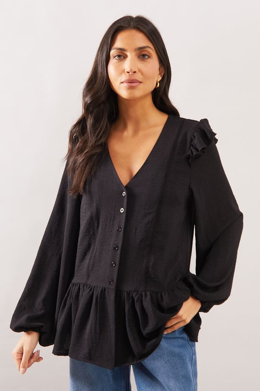 Elegant V-neckline with button-through front detail
        Charming shoulder ruffle trim for a feminine touch
        Relaxed smock silhouette with gathered peplum hem
        Voluminous long sleeves with subtle gathering at cuffs
        Delicate lace trim detailing adds sophisticated texture
    
    This Wallis woven smock top combines comfort with sophisticated style. The flattering V-neckline frames the dcolletage beautifully, whilst the ruffle trim at the shoulders adds a touch of playful femininity. The relaxed fit and peplum hem create a figure-flattering silhouette that drapes gracefully over the body. Style with wide-leg jeans and flat sandals as seen on our model for a chic daytime look perfect for weekend brunches or casual family gatherings. Alternatively, pair with tailored trousers and ballet flats for a smart-casual ensemble ideal for lunch dates or shopping trips. The versatile design transitions effortlessly from day to evening - simply swap your flats for a block heel and add statement earrings for dinner with friends.