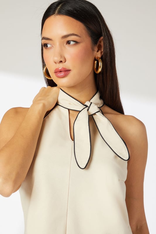 Elegant halterneck design with distinctive contrast piping detail
        Crafted from a breathable linen-cotton blend for all-day comfort
        Sleeveless silhouette with a relaxed fit through the body
        Sophisticated tie detail at the neck for adjustable styling
        Keyhole back fastening adds a subtle touch of refinement
    
    This Principles halterneck top combines effortless style with versatile daywear appeal. The contrast piping detail creates visual interest while the natural fabric blend ensures breathability for warm-weather comfort. Style with wide-leg trousers as shown for a balanced silhouette that works beautifully for lunch dates or gallery visits. For casual weekend outings, pair with your favourite denim and trainers, adding a structured crossbody bag for practical chic. The neutral tone makes this top an excellent canvas for statement jewellery - try bold earrings to draw attention to the elegant neckline. Perfect for family gatherings or informal brunches, this top transitions seamlessly from day to evening with a simple change of accessories. The timeless design ensures this piece will remain a wardrobe favourite for seasons to come.