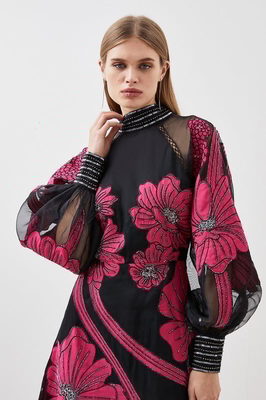 Feel formal in our maxi dress, made with high quality organdie fabric, featuring a fit and flare silhouette that flatters the curves, as well as floral applique accents. Style it with court heels or heeled boots for a look that will take you from party nights and wedding guest days. Applique Organdie Floral Graphic Maxi Dress High Quality Organdie Fabric Comfortable Fit and Flare Silhouette Long Balloon Sleeves Formal, High Neckline Flowing, Sheer Overlay Large, Floral Design Keyhole Back Accent Large Bow Feature Zip Back FasteningBrowse this seasons mother of the bride dresses or shop the full collection of women's wedding outfits now.