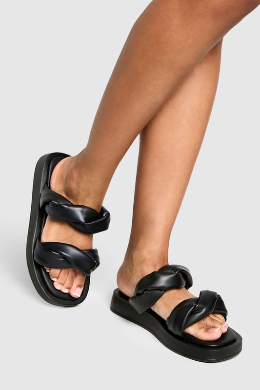 Wide fit design for enhanced comfort and easy wear
        Distinctive twisted strap detail adding contemporary flair
        Flat sole with height between 0-2cm for all-day wearability
        Smooth PU construction offering a sleek, polished finish
        Cushioned footbed providing essential support for extended wear
    
    These statement slides redefine casual footwear with their eye-catching twisted strap detail. The wide fit design ensures maximum comfort whilst the flat sole makes them perfect for those busy days when style can't compromise practicality. Pair with cropped wide-leg trousers and an oversized linen shirt for a sophisticated daytime look, or team with a flowing maxi dress for relaxed weekend brunches. The versatile design transitions effortlessly from poolside lounging to casual city strolls. Their minimalist aesthetic works brilliantly with both neutral tones and vibrant outfits, making them a wardrobe essential for the fashion-forward woman who values both comfort and contemporary style. Ideal for family gatherings, festival outings, or holiday explorations when you need footwear that's as reliable as it is stylish.