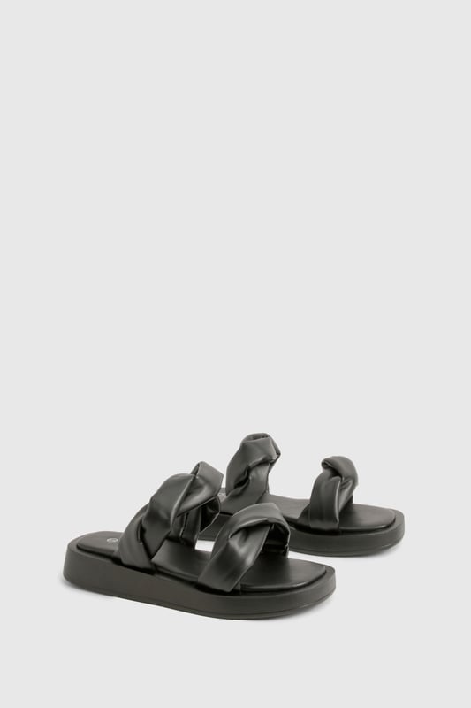 Wide fit design for enhanced comfort and easy wear
        Distinctive twisted strap detail adding contemporary flair
        Flat sole with height between 0-2cm for all-day wearability
        Smooth PU construction offering a sleek, polished finish
        Cushioned footbed providing essential support for extended wear
    
    These statement slides redefine casual footwear with their eye-catching twisted strap detail. The wide fit design ensures maximum comfort whilst the flat sole makes them perfect for those busy days when style can't compromise practicality. Pair with cropped wide-leg trousers and an oversized linen shirt for a sophisticated daytime look, or team with a flowing maxi dress for relaxed weekend brunches. The versatile design transitions effortlessly from poolside lounging to casual city strolls. Their minimalist aesthetic works brilliantly with both neutral tones and vibrant outfits, making them a wardrobe essential for the fashion-forward woman who values both comfort and contemporary style. Ideal for family gatherings, festival outings, or holiday explorations when you need footwear that's as reliable as it is stylish.