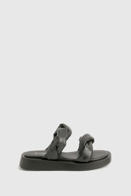 Wide fit design for enhanced comfort and easy wear
        Distinctive twisted strap detail adding contemporary flair
        Flat sole with height between 0-2cm for all-day wearability
        Smooth PU construction offering a sleek, polished finish
        Cushioned footbed providing essential support for extended wear
    
    These statement slides redefine casual footwear with their eye-catching twisted strap detail. The wide fit design ensures maximum comfort whilst the flat sole makes them perfect for those busy days when style can't compromise practicality. Pair with cropped wide-leg trousers and an oversized linen shirt for a sophisticated daytime look, or team with a flowing maxi dress for relaxed weekend brunches. The versatile design transitions effortlessly from poolside lounging to casual city strolls. Their minimalist aesthetic works brilliantly with both neutral tones and vibrant outfits, making them a wardrobe essential for the fashion-forward woman who values both comfort and contemporary style. Ideal for family gatherings, festival outings, or holiday explorations when you need footwear that's as reliable as it is stylish.