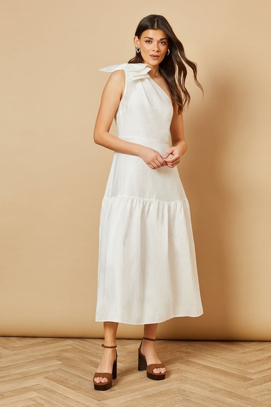 Striking one-shoulder design with an elegant oversized bow detail
        Feminine midi length with a flattering tiered skirt
        Lightweight Tencel fabric that drapes beautifully
        Clean, minimalist silhouette perfect for special occasions
        Versatile design that can be dressed up or down with accessories
    
    This enchanting one-shoulder midi dress showcases Oasis's signature feminine aesthetic with its standout bow shoulder detail. The graceful tiered skirt creates movement and dimension whilst maintaining a sophisticated silhouette. Style with strappy heeled sandals and statement earrings for summer weddings or garden parties. For race day events, pair with a fascinator and clutch bag for a refined ensemble. The versatile design transitions beautifully from daytime celebrations to evening soires-simply switch your accessories to match the occasion. The clean lines and classic shape make this dress a timeless addition to your occasion wardrobe, whilst the midi length offers both elegance and practicality. Perfect for those moments when you want to make a subtle yet memorable impression.