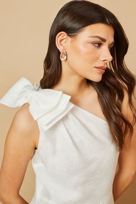 Striking one-shoulder design with an elegant oversized bow detail
        Feminine midi length with a flattering tiered skirt
        Lightweight Tencel fabric that drapes beautifully
        Clean, minimalist silhouette perfect for special occasions
        Versatile design that can be dressed up or down with accessories
    
    This enchanting one-shoulder midi dress showcases Oasis's signature feminine aesthetic with its standout bow shoulder detail. The graceful tiered skirt creates movement and dimension whilst maintaining a sophisticated silhouette. Style with strappy heeled sandals and statement earrings for summer weddings or garden parties. For race day events, pair with a fascinator and clutch bag for a refined ensemble. The versatile design transitions beautifully from daytime celebrations to evening soires-simply switch your accessories to match the occasion. The clean lines and classic shape make this dress a timeless addition to your occasion wardrobe, whilst the midi length offers both elegance and practicality. Perfect for those moments when you want to make a subtle yet memorable impression.