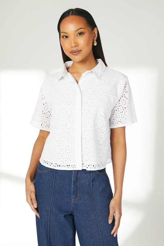 Intricate broderie anglaise pattern throughout
        Collared neckline for a polished look
        Short sleeves with scalloped edges
        Boxy fit for a relaxed silhouette
        Button-down front closure
    
    This charming broderie cotton T-shirt from Principles is a versatile addition to your warm-weather wardrobe. The delicate eyelet detailing adds a touch of femininity, while the boxy fit ensures comfort for all-day wear. Style it with wide-leg trousers and sandals for a chic daytime look perfect for brunches or casual outings. For a more laid-back ensemble, pair it with your favourite denim shorts and trainers for a weekend stroll. The collared neckline allows for easy accessorising - add a dainty necklace to draw attention to the dcolletage. This T-shirt is ideal for various casual events, from family gatherings to shopping trips with friends. Its breathable cotton fabric makes it a go-to choice for balmy summer days, keeping you cool and stylish.