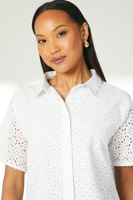 Intricate broderie anglaise pattern throughout
        Collared neckline for a polished look
        Short sleeves with scalloped edges
        Boxy fit for a relaxed silhouette
        Button-down front closure
    
    This charming broderie cotton T-shirt from Principles is a versatile addition to your warm-weather wardrobe. The delicate eyelet detailing adds a touch of femininity, while the boxy fit ensures comfort for all-day wear. Style it with wide-leg trousers and sandals for a chic daytime look perfect for brunches or casual outings. For a more laid-back ensemble, pair it with your favourite denim shorts and trainers for a weekend stroll. The collared neckline allows for easy accessorising - add a dainty necklace to draw attention to the dcolletage. This T-shirt is ideal for various casual events, from family gatherings to shopping trips with friends. Its breathable cotton fabric makes it a go-to choice for balmy summer days, keeping you cool and stylish.