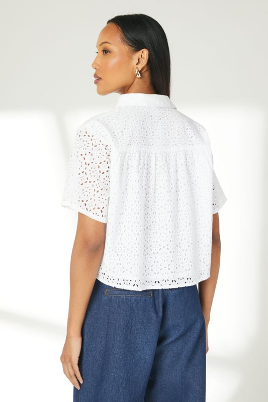 Intricate broderie anglaise pattern throughout
        Collared neckline for a polished look
        Short sleeves with scalloped edges
        Boxy fit for a relaxed silhouette
        Button-down front closure
    
    This charming broderie cotton T-shirt from Principles is a versatile addition to your warm-weather wardrobe. The delicate eyelet detailing adds a touch of femininity, while the boxy fit ensures comfort for all-day wear. Style it with wide-leg trousers and sandals for a chic daytime look perfect for brunches or casual outings. For a more laid-back ensemble, pair it with your favourite denim shorts and trainers for a weekend stroll. The collared neckline allows for easy accessorising - add a dainty necklace to draw attention to the dcolletage. This T-shirt is ideal for various casual events, from family gatherings to shopping trips with friends. Its breathable cotton fabric makes it a go-to choice for balmy summer days, keeping you cool and stylish.