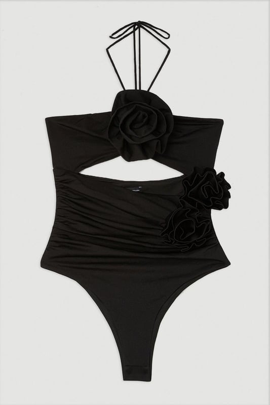 Welcome the sun with a swimming costume that will turn heads, featuring a three dimensional corsage accent on the bust and hip, and a statement cut out design in the front and back. Style this piece with strappy sandals and a beach cover up for a holiday look that can be reworn time and time again. Rosette Cut Out Detail Swimsuit Flattering Halter Neckline Unique, Three Dimensional Flower Accent Statement Cut Out Design Tie and Clasp Fastening in Back