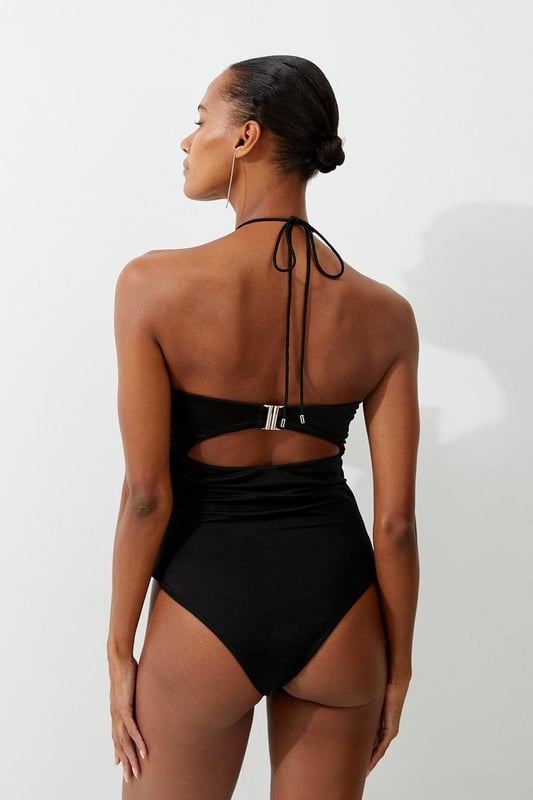 Welcome the sun with a swimming costume that will turn heads, featuring a three dimensional corsage accent on the bust and hip, and a statement cut out design in the front and back. Style this piece with strappy sandals and a beach cover up for a holiday look that can be reworn time and time again. Rosette Cut Out Detail Swimsuit Flattering Halter Neckline Unique, Three Dimensional Flower Accent Statement Cut Out Design Tie and Clasp Fastening in Back