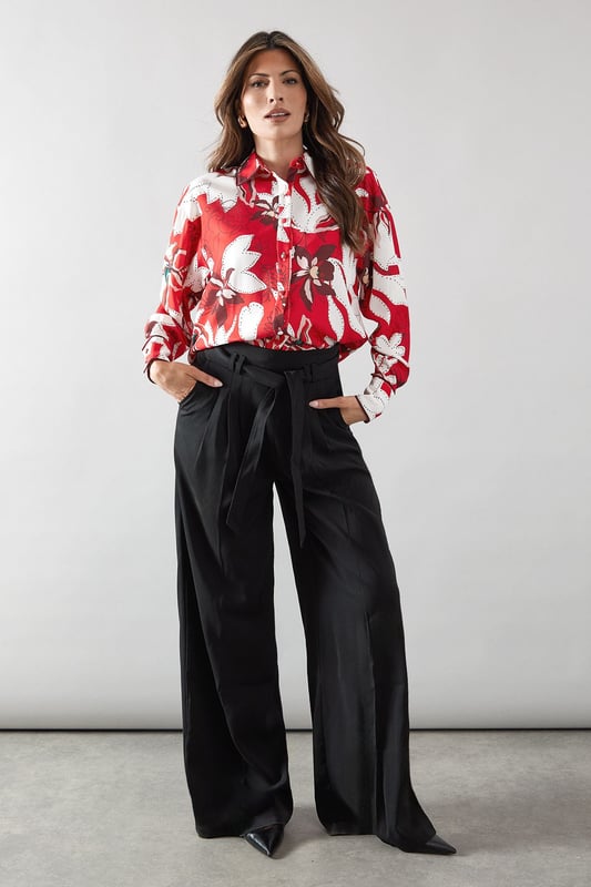 Bold floral print shirt with distinctive piping detail for a sophisticated edge
        Classic collared neckline with full button-through front closure
        Relaxed fit silhouette offering comfortable all-day wear
        Practical chest pocket adding both style and functionality
        Long sleeves with button cuffs for versatile styling options
    
    This striking Wallis shirt combines eye-catching floral patterns with elegant piping details for a piece that commands attention. The relaxed silhouette creates a flattering drape that works beautifully with the woven fabric, while the practical chest pocket adds a touch of casual charm. Style this versatile top with wide-leg trousers as shown for a sophisticated daytime look perfect for family gatherings or lunch with friends. For a more casual approach, pair with your favourite denim and trainers for weekend outings. The collared design can be worn fully buttoned for a polished appearance or with the top buttons undone for a more relaxed feel. This shirt transitions effortlessly from casual coffee dates to smart-casual office environments, making it an indispensable addition to your wardrobe.