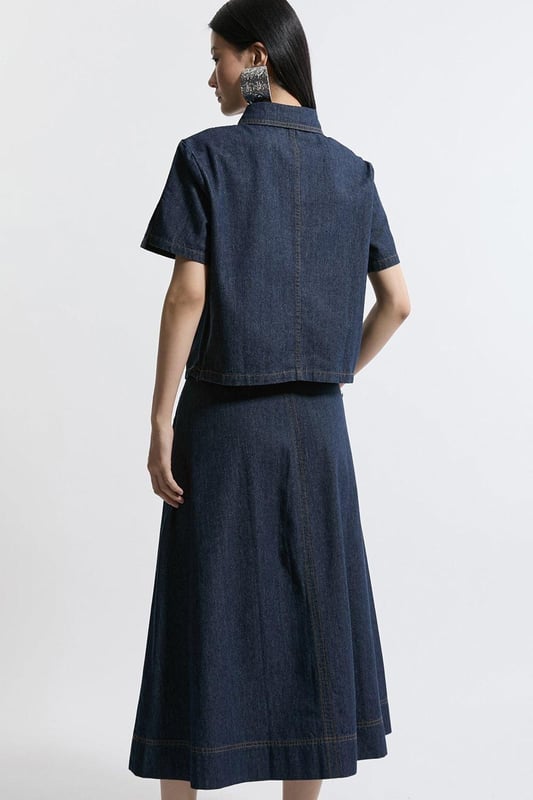 This Karen Millen denim midi skirt is a versatile wardrobe staple that effortlessly bridges the gap between casual and smart-casual attire. The full, flared silhouette creates a graceful movement as you walk, while the high-waisted design accentuates your natural curves. Style it with a fitted knit top and ankle boots for a stylish daytime look, perfect for weekend brunches or casual family gatherings. For a more relaxed vibe, pair it with a simple t-shirt and trainers. The side pockets add a practical touch, ideal for keeping small essentials close at hand. This skirt's adaptable nature makes it suitable for various occasions, from laid-back office days to informal evening outings. Its timeless design ensures it will remain a go-to piece in your wardrobe for seasons to come.  Midi-length denim skirt with a full, flared silhouette High-waisted design for a flattering fit Side pockets for practicality and style Versatile cotton fabric suitable for various seasons Subtle A-line shape creates a feminine profile