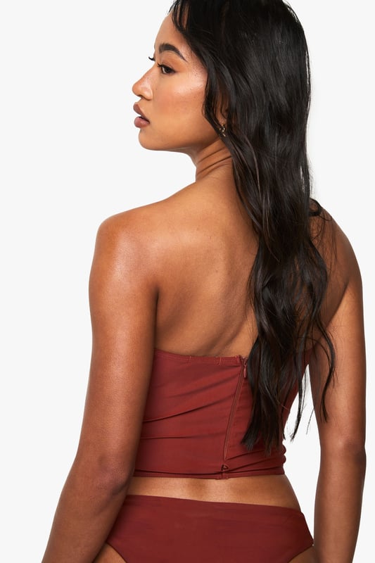 Structured corset-style tankini top with flattering seam detailing
        Strapless bandeau design with supportive boning for shape retention
        Fitted silhouette that accentuates the waistline
        Stretchy knitted fabric for comfortable all-day wear
        Coordinating bottoms complete the two-piece swimwear set
    
    Make a statement poolside with this striking Korsett Tankini-Bikinioberteil from Boohoo. The corset-inspired design brings runway fashion to beachwear, creating a silhouette that's both flattering and fashion-forward. Style with oversized sunglasses and layered jewellery as seen on our model for an Instagram-worthy holiday look. Perfect for lounging by the pool or strolling along the beach, this versatile piece transitions effortlessly from daytime sunbathing to sunset beach club gatherings. For a complete ensemble, pair with a flowing kimono and metallic sandals when moving from poolside to beachfront restaurant. The structured design offers more coverage than a traditional bikini whilst maintaining that head-turning appeal that Boohoo is known for.