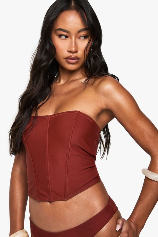 Structured corset-style tankini top with flattering seam detailing
        Strapless bandeau design with supportive boning for shape retention
        Fitted silhouette that accentuates the waistline
        Stretchy knitted fabric for comfortable all-day wear
        Coordinating bottoms complete the two-piece swimwear set
    
    Make a statement poolside with this striking Korsett Tankini-Bikinioberteil from Boohoo. The corset-inspired design brings runway fashion to beachwear, creating a silhouette that's both flattering and fashion-forward. Style with oversized sunglasses and layered jewellery as seen on our model for an Instagram-worthy holiday look. Perfect for lounging by the pool or strolling along the beach, this versatile piece transitions effortlessly from daytime sunbathing to sunset beach club gatherings. For a complete ensemble, pair with a flowing kimono and metallic sandals when moving from poolside to beachfront restaurant. The structured design offers more coverage than a traditional bikini whilst maintaining that head-turning appeal that Boohoo is known for.