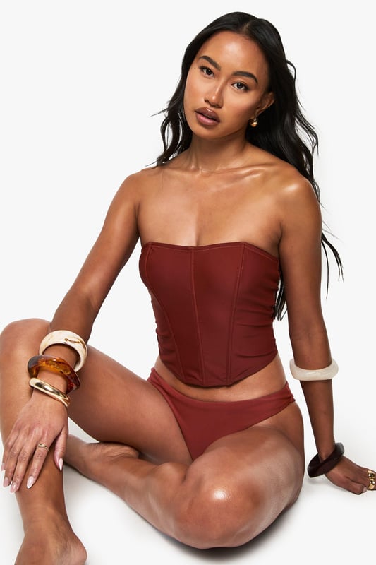 Structured corset-style tankini top with flattering seam detailing
        Strapless bandeau design with supportive boning for shape retention
        Fitted silhouette that accentuates the waistline
        Stretchy knitted fabric for comfortable all-day wear
        Coordinating bottoms complete the two-piece swimwear set
    
    Make a statement poolside with this striking Korsett Tankini-Bikinioberteil from Boohoo. The corset-inspired design brings runway fashion to beachwear, creating a silhouette that's both flattering and fashion-forward. Style with oversized sunglasses and layered jewellery as seen on our model for an Instagram-worthy holiday look. Perfect for lounging by the pool or strolling along the beach, this versatile piece transitions effortlessly from daytime sunbathing to sunset beach club gatherings. For a complete ensemble, pair with a flowing kimono and metallic sandals when moving from poolside to beachfront restaurant. The structured design offers more coverage than a traditional bikini whilst maintaining that head-turning appeal that Boohoo is known for.