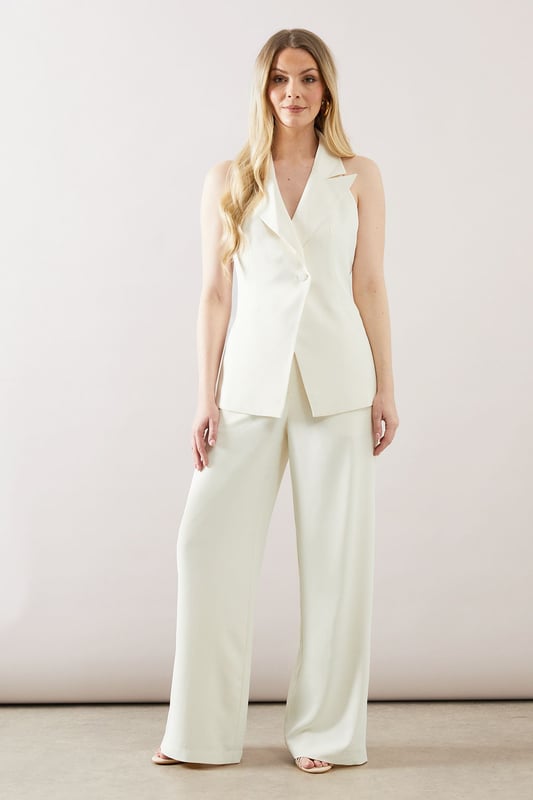 Sleek longline waistcoat with a sophisticated collar
        Halterneck design for a modern, chic look
        Wide-leg trousers with a flattering high waist
        Side pockets for practicality and style
        Back split detail on trousers for ease of movement
    
    This collared longline waistcoat ensemble from Wallis is the epitome of contemporary sophistication. Perfect for the woman who appreciates glamour with a comfortable edge, this set is versatile enough for various occasions. The sleek waistcoat, featuring a halterneck design, pairs beautifully with the wide-leg trousers, creating a flowing silhouette that's both flattering and on-trend. For a casual yet polished look, style with minimalist jewellery and strappy sandals. When attending family gatherings or informal events, layer with a lightweight blouse underneath for added dimension. The ensemble's clean lines and elegant simplicity make it an ideal choice for those seeking a refined appearance without sacrificing comfort. Customise the look with a statement belt to define the waist or leave it open for a more relaxed feel. This Wallis piece promises to be a versatile addition to your wardrobe, ready to take you from day to night with effortless grace.