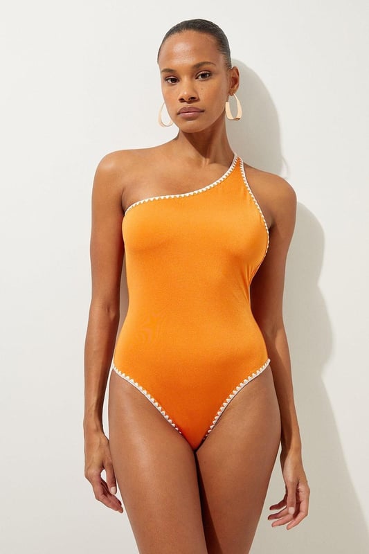 Welcome the sun with a swimsuit that will turn heads, featuring a statement one shoulder design, contrasting stitch details, and a low back. Style this piece with strappy sandals and a beach cover up for a holiday look that can be reworn time and time again. Stitch Detail One Shoulder Cut Out Swimsuit Contrasting Stitch Accents Flattering One Shoulder Design Statement Open Back