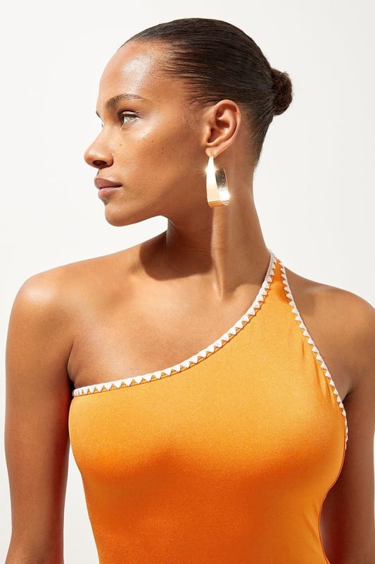 Welcome the sun with a swimsuit that will turn heads, featuring a statement one shoulder design, contrasting stitch details, and a low back. Style this piece with strappy sandals and a beach cover up for a holiday look that can be reworn time and time again. Stitch Detail One Shoulder Cut Out Swimsuit Contrasting Stitch Accents Flattering One Shoulder Design Statement Open Back