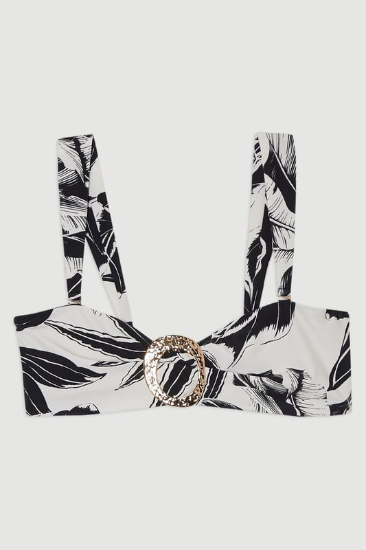 Make a statement this summer with Karen Millen's slinky bandeau bikini top. The bold palm print design captures the essence of a tropical getaway, whilst the bandeau style with removable straps provides flexibility, allowing you to switch between strapless and halter styles to suit your mood. The metallic ring detail at the centre adds a touch of glamour, perfect for catching the sunlight as you lounge by the pool. Pair with the matching bottoms for a coordinated look, or mix and match for a personalised ensemble. Whether you're jetting off to a sun-soaked destination or enjoying a staycation, this versatile top is a must-have for your summer wardrobe. Style with oversized sunglasses and a wide-brimmed hat for the ultimate beach-ready look.  Striking palm print design Bandeau style with removable straps for versatile wear Eye-catching metallic ring detail at centre front Stretchy fabric blend for comfortable fit Coordinating bottoms available for a complete set