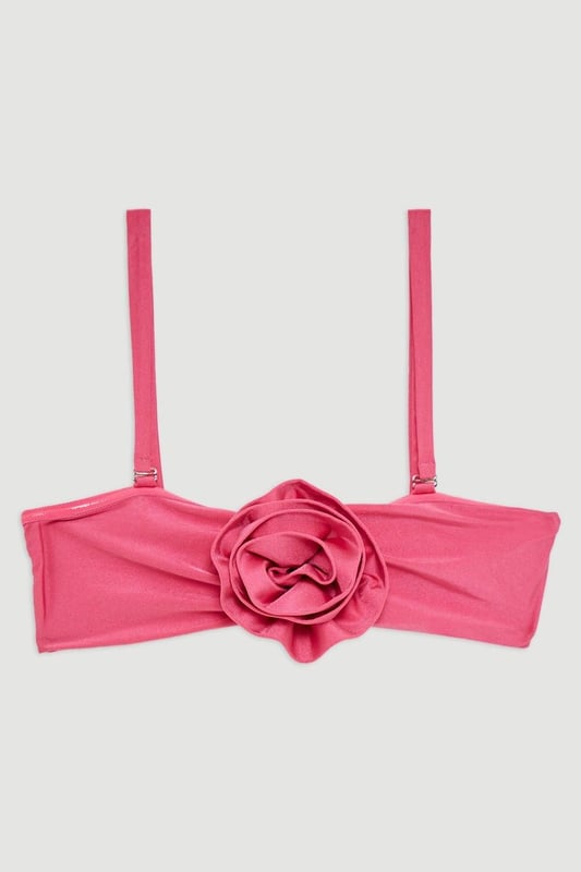 Welcome the sun with a bikini that will turn heads, the top of which features a three dimensional corsage accent at the cleavage, and a comfortable bandeau style, with optional, wide shoulder straps. Style this piece with the matching bikini bottoms, strappy sandals, and a beach cover up for a holiday look that can be reworn time and time again. Rosette Detail Bandeau Bikini Top Comfortable Bandeau Style Unique, Three Dimensional Flower Accent at Cleavage Optional, Wide Shoulder Straps Clasp Fastening in Back Matching Bikini Bottoms Sold Separately