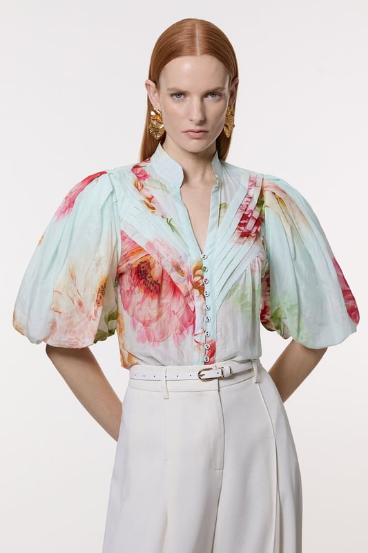 Silk Cotton Short Sleeve Pintuck Woven Blouse This Karen Millen woven blouse radiates refinement and charm, perfect for those seeking a statement piece for formal occasions. The pintuck detailing along the front adds texture and visual interest, while the high neckline lends an air of sophistication. The voluminous short sleeves create a dramatic silhouette, balancing the loose fit of the body. Style this blouse with tailored trousers and pointed-toe heels for a polished look at weddings or corporate events. For a more relaxed yet stylish ensemble, pair it with a sleek pencil skirt and strappy sandals. The versatility of this piece allows for effortless transition from day to evening wear, making it a valuable addition to any wardrobe. Accessorise with delicate gold jewellery to complement the blouse's elegant design and create a cohesive, stylish appearance. Exquisite silk-cotton blend for luxurious comfort Striking pintuck detailing along the front placket Voluminous short sleeves for a dramatic silhouette High neckline adds sophistication and elegance Button-front closure for easy wear and versatility