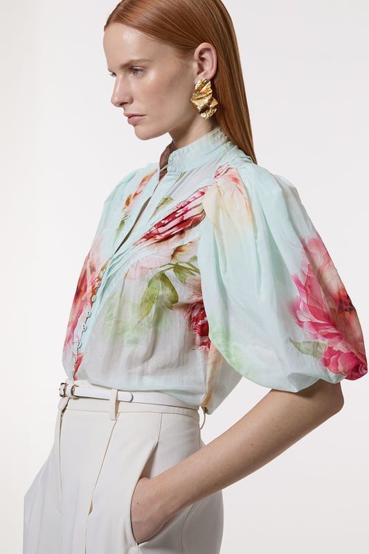 Silk Cotton Short Sleeve Pintuck Woven Blouse This Karen Millen woven blouse radiates refinement and charm, perfect for those seeking a statement piece for formal occasions. The pintuck detailing along the front adds texture and visual interest, while the high neckline lends an air of sophistication. The voluminous short sleeves create a dramatic silhouette, balancing the loose fit of the body. Style this blouse with tailored trousers and pointed-toe heels for a polished look at weddings or corporate events. For a more relaxed yet stylish ensemble, pair it with a sleek pencil skirt and strappy sandals. The versatility of this piece allows for effortless transition from day to evening wear, making it a valuable addition to any wardrobe. Accessorise with delicate gold jewellery to complement the blouse's elegant design and create a cohesive, stylish appearance. Exquisite silk-cotton blend for luxurious comfort Striking pintuck detailing along the front placket Voluminous short sleeves for a dramatic silhouette High neckline adds sophistication and elegance Button-front closure for easy wear and versatility