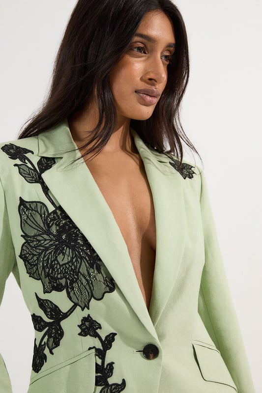 This Karen Millen tailored jacket transforms any ensemble with its exquisite placed floral lace embroidery. The regular fit provides comfortable structure while maintaining a sophisticated silhouette that works beautifully for formal occasions. As seen on our model, pair with sleek black trousers for a contemporary take on evening attire, or style with a coordinating skirt for wedding season elegance. The collared design and single-button closure create a flattering V-shaped opening that elongates the torso. Perfect for summer garden parties, race day events or evening receptions, this jacket offers versatility beyond the ordinary. Layer over a simple camisole or wear with confidence as a statement piece in its own right. The intricate embroidery detail ensures you'll command attention at any formal gathering.  Striking floral lace embroidery creates a dramatic statement across the jacket Tailored silhouette with structured shoulders and a single-button fastening Collared neckline adds a refined touch to this occasion piece Functional front pockets provide both style and practicality Viscose linen blend offers a lightweight feel with natural texture