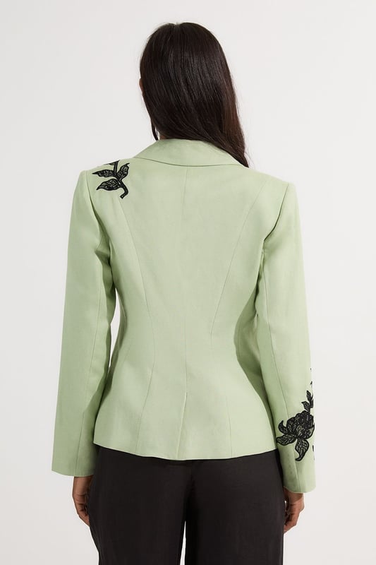 This Karen Millen tailored jacket transforms any ensemble with its exquisite placed floral lace embroidery. The regular fit provides comfortable structure while maintaining a sophisticated silhouette that works beautifully for formal occasions. As seen on our model, pair with sleek black trousers for a contemporary take on evening attire, or style with a coordinating skirt for wedding season elegance. The collared design and single-button closure create a flattering V-shaped opening that elongates the torso. Perfect for summer garden parties, race day events or evening receptions, this jacket offers versatility beyond the ordinary. Layer over a simple camisole or wear with confidence as a statement piece in its own right. The intricate embroidery detail ensures you'll command attention at any formal gathering.  Striking floral lace embroidery creates a dramatic statement across the jacket Tailored silhouette with structured shoulders and a single-button fastening Collared neckline adds a refined touch to this occasion piece Functional front pockets provide both style and practicality Viscose linen blend offers a lightweight feel with natural texture