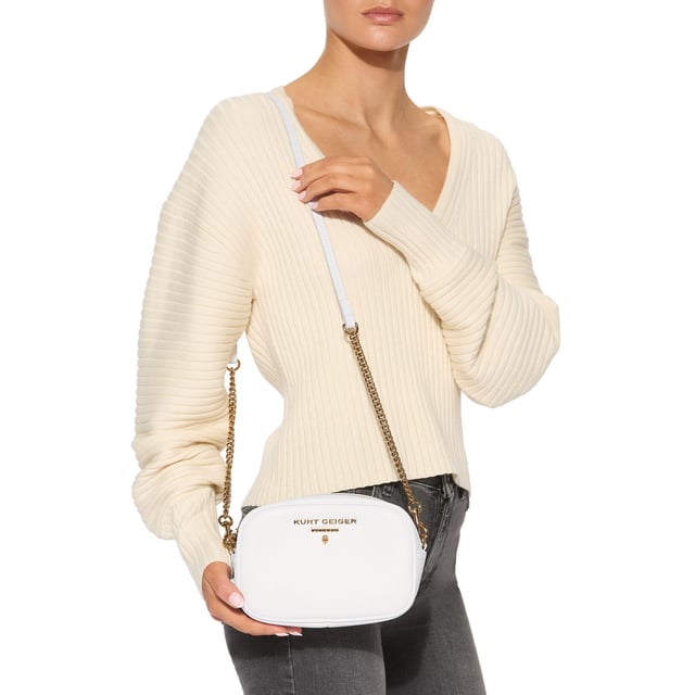 This Kurt Geiger Small Chiswick Camera Bag features a white pebble grain leather exterior. There is an antiqued brass logo and micro eagle head on the front of the bag and open pocket on the back. Dimensions: 13cm (H), 19cm (L), 6cm (D). Strap length: 236cm.