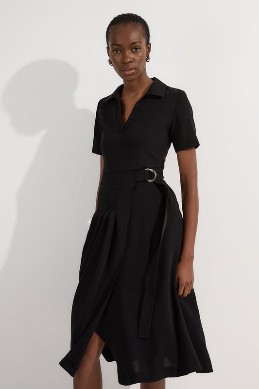 This Karen Millen soft tailored midi dress strikes the perfect balance between professional polish and feminine charm. The classic collared design and pleated detailing create a sophisticated silhouette that commands attention in any boardroom or office setting. Style with pointed court shoes and a structured tote for daytime meetings, or transition to evening networking events with statement earrings and a sleek clutch. The belted waist offers customisable definition, whilst the midi length ensures appropriate coverage for formal workplace settings. This versatile piece works beautifully layered under a tailored blazer during cooler months or worn alone when temperatures rise. A timeless addition to your workwear rotation that delivers effortless elegance with practical comfort.  Elegant collared neckline with a sophisticated V-opening for a refined workwear silhouette Short sleeves offering comfortable coverage whilst maintaining a professional appearance Stylish D-ring belt detail that cinches the waist for a flattering, feminine shape Graceful pleated skirt with a flowing midi length that creates elegant movement Practical side pockets discreetly integrated into the design for functionality