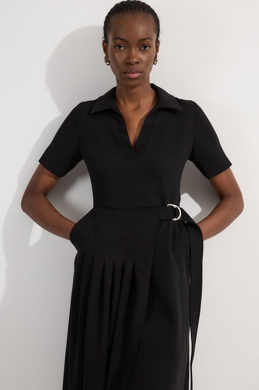 This Karen Millen soft tailored midi dress strikes the perfect balance between professional polish and feminine charm. The classic collared design and pleated detailing create a sophisticated silhouette that commands attention in any boardroom or office setting. Style with pointed court shoes and a structured tote for daytime meetings, or transition to evening networking events with statement earrings and a sleek clutch. The belted waist offers customisable definition, whilst the midi length ensures appropriate coverage for formal workplace settings. This versatile piece works beautifully layered under a tailored blazer during cooler months or worn alone when temperatures rise. A timeless addition to your workwear rotation that delivers effortless elegance with practical comfort.  Elegant collared neckline with a sophisticated V-opening for a refined workwear silhouette Short sleeves offering comfortable coverage whilst maintaining a professional appearance Stylish D-ring belt detail that cinches the waist for a flattering, feminine shape Graceful pleated skirt with a flowing midi length that creates elegant movement Practical side pockets discreetly integrated into the design for functionality