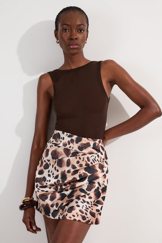 Make a statement at your next soiree with this captivating animal print mini skirt, featuring ruched detail for a figure-flattering silhouette. Pair it with a sleek bodysuit or a crisp white blouse for a sophisticated ensemble perfect for cocktail parties or upscale dinners. For a more daring look, team it with a matching animal print top and strappy heels. The versatile design allows for both dressed-up and casual styling options; wear it with a leather jacket and ankle boots for a chic day-to-night transition. This skirt is an ideal choice for those seeking to inject a touch of wild glamour into their wardrobe, suitable for a range of occasions from formal events to nights out on the town.  Striking animal print pattern for a bold, eye-catching look Ruched detailing adds texture and flattering dimension Structured viscose satin fabric offers a luxurious feel and drape Mini length design for a flirty, leg-lengthening effect High-waisted silhouette accentuates the waistline