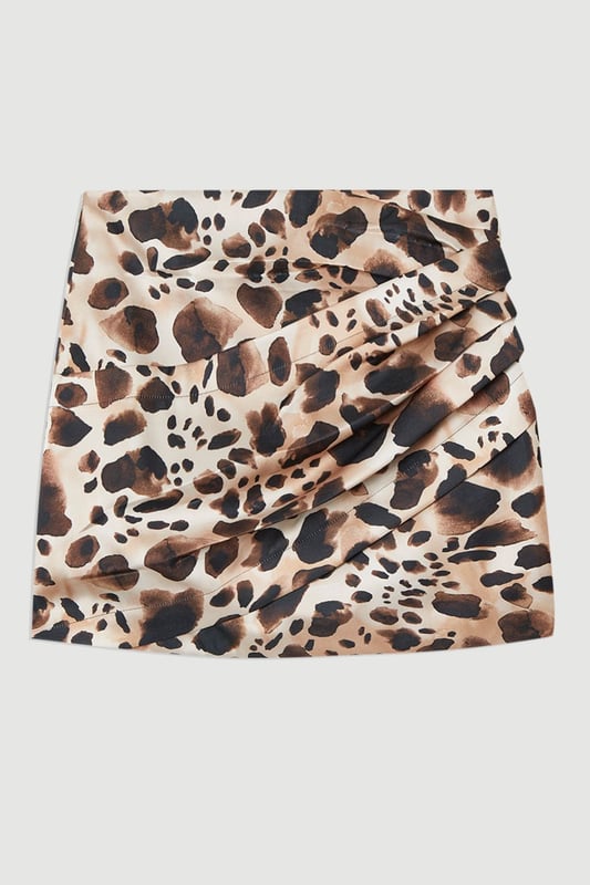 Make a statement at your next soiree with this captivating animal print mini skirt, featuring ruched detail for a figure-flattering silhouette. Pair it with a sleek bodysuit or a crisp white blouse for a sophisticated ensemble perfect for cocktail parties or upscale dinners. For a more daring look, team it with a matching animal print top and strappy heels. The versatile design allows for both dressed-up and casual styling options; wear it with a leather jacket and ankle boots for a chic day-to-night transition. This skirt is an ideal choice for those seeking to inject a touch of wild glamour into their wardrobe, suitable for a range of occasions from formal events to nights out on the town.  Striking animal print pattern for a bold, eye-catching look Ruched detailing adds texture and flattering dimension Structured viscose satin fabric offers a luxurious feel and drape Mini length design for a flirty, leg-lengthening effect High-waisted silhouette accentuates the waistline