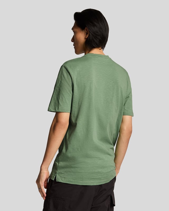 Das Lyle & Scott Cotton Slub T-Shirt ist eine zeitlose Silhouette aus neuen Materialien und wurde von den britischen Küstengemeinden inspiriert. Das 100 % Baumwoll-Slub-Material sorgt für eine robuste Textur, während der gerippte Kragen und die detailreichen Nähte dieses T-Shirt zu einem vielseitigen Begleiter machen, der perfekt zu Jeans oder Chinos passt. Mit dem charakteristischen Golden Eagle.