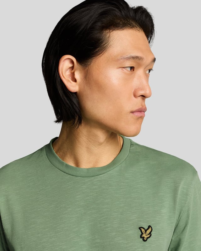 Das Lyle & Scott Cotton Slub T-Shirt ist eine zeitlose Silhouette aus neuen Materialien und wurde von den britischen Küstengemeinden inspiriert. Das 100 % Baumwoll-Slub-Material sorgt für eine robuste Textur, während der gerippte Kragen und die detailreichen Nähte dieses T-Shirt zu einem vielseitigen Begleiter machen, der perfekt zu Jeans oder Chinos passt. Mit dem charakteristischen Golden Eagle.