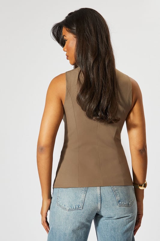 Tailored High Neck Waistcoat Sleek high neck design for a sophisticated look
Tailored fit accentuates the waistline
Unique button-front closure adds visual interest
Versatile sleeveless style perfect for layering
Asymmetrical hem creates a modern silhouette
Make a bold statement with this tailored high neck waistcoat from MissPap. This eye-catching piece combines classic tailoring with contemporary flair, perfect for the fashion-forward woman who loves to stand out. The sleek high neck and button-front closure create a polished look, while the asymmetrical hem adds a touch of edginess. Style it with wide-leg trousers and strappy heels for a chic evening ensemble, or layer it over a crisp white shirt and pair with jeans for a smart-casual daytime look. The versatile design makes it ideal for various occasions, from casual gatherings to nights out on the town. This waistcoat is a must-have addition to any wardrobe, offering endless styling possibilities and ensuring you'll always be the centre of attention.