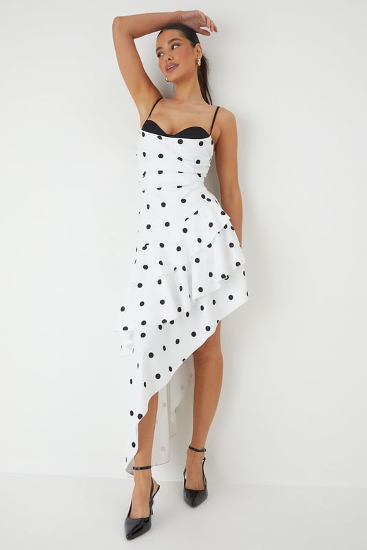 Striking sweetheart neckline with contrasting trim for a bold statement
        Asymmetric layered frill design creates dramatic movement and visual interest
        Elegant maxi length with high-low hemline for a contemporary silhouette
        Adjustable thin straps for a customised and secure fit
        Playful polka dot pattern adds a timeless charm to this occasion piece
    
    Make an unforgettable entrance in this show-stopping polka dot maxi dress from MissPap. The layered frill construction cascades beautifully to create a flattering asymmetric hemline that dances with your every move. The structured sweetheart neckline with its contrasting trim frames your dcolletage perfectly, whilst the fitted bodice cinches the waist for a feminine silhouette. Style with strappy heels and statement earrings as seen on our model for formal events such as weddings or race days. For evening soires, add a sleek clutch and a bold red lip to command attention. This versatile piece transitions effortlessly from daytime garden parties to evening celebrations - simply switch your accessories to reflect the occasion's formality. The lightweight woven fabric ensures comfort without compromising on sophistication.