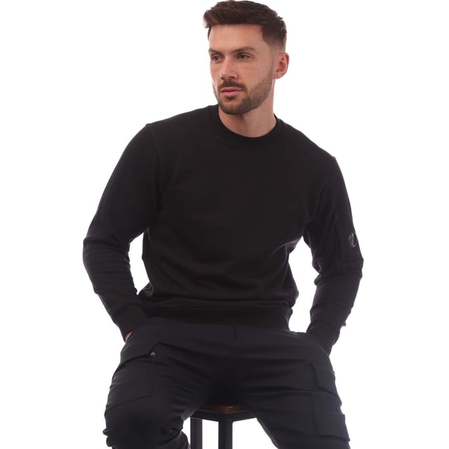 Mens C.P. Company Diagonal Raised Fleece Lens Crewneck Sweatshirt in black.- Ribbed crewneck.- Ribbed cuffs and hem. - Sleeve pocket with lens detail.- Regular fit.- 100% Cotton.- Ref: 18CMSS023A999