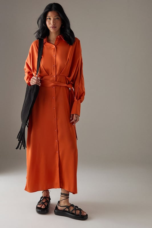 Striking batwing sleeves for a dramatic silhouette
        Elegant midi length with a daring side split
        Collared neckline adds a touch of sophistication
        Button-down front for versatile styling options
        Cinched waist design creates a flattering shape
    
    This satin shirt dress from Warehouse is a versatile piece that effortlessly transitions from day to night. The batwing sleeves create a bold, contemporary look, while the midi length with a side split adds a hint of allure. Perfect for confident women who appreciate edgy yet feminine styles, this dress can be styled for various casual occasions. For a chic daytime ensemble, pair it with ankle boots and a crossbody bag for a family lunch or weekend outing. Layer with a leather jacket for an edgier look when meeting friends for coffee. The button-down front allows for customisable coverage, making it suitable for different settings. Accessorise with statement earrings and a sleek updo for an evening dinner date. The dress's fluid silhouette and rich texture make it a standout piece in any wardrobe, ideal for those who want to make a subtle yet impactful fashion statement.