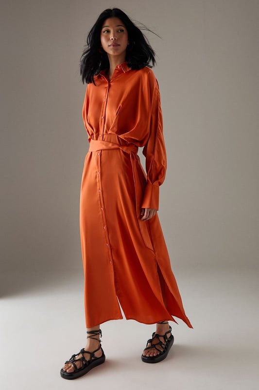 Striking batwing sleeves for a dramatic silhouette
        Elegant midi length with a daring side split
        Collared neckline adds a touch of sophistication
        Button-down front for versatile styling options
        Cinched waist design creates a flattering shape
    
    This satin shirt dress from Warehouse is a versatile piece that effortlessly transitions from day to night. The batwing sleeves create a bold, contemporary look, while the midi length with a side split adds a hint of allure. Perfect for confident women who appreciate edgy yet feminine styles, this dress can be styled for various casual occasions. For a chic daytime ensemble, pair it with ankle boots and a crossbody bag for a family lunch or weekend outing. Layer with a leather jacket for an edgier look when meeting friends for coffee. The button-down front allows for customisable coverage, making it suitable for different settings. Accessorise with statement earrings and a sleek updo for an evening dinner date. The dress's fluid silhouette and rich texture make it a standout piece in any wardrobe, ideal for those who want to make a subtle yet impactful fashion statement.
