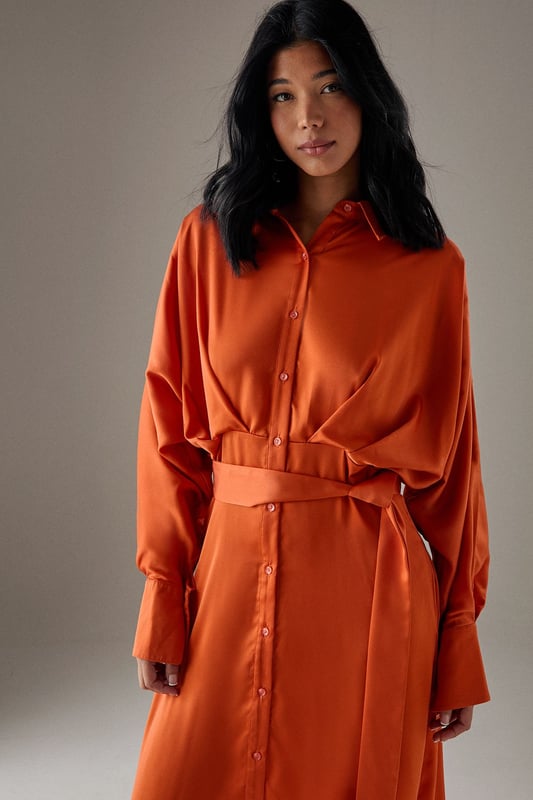 Striking batwing sleeves for a dramatic silhouette
        Elegant midi length with a daring side split
        Collared neckline adds a touch of sophistication
        Button-down front for versatile styling options
        Cinched waist design creates a flattering shape
    
    This satin shirt dress from Warehouse is a versatile piece that effortlessly transitions from day to night. The batwing sleeves create a bold, contemporary look, while the midi length with a side split adds a hint of allure. Perfect for confident women who appreciate edgy yet feminine styles, this dress can be styled for various casual occasions. For a chic daytime ensemble, pair it with ankle boots and a crossbody bag for a family lunch or weekend outing. Layer with a leather jacket for an edgier look when meeting friends for coffee. The button-down front allows for customisable coverage, making it suitable for different settings. Accessorise with statement earrings and a sleek updo for an evening dinner date. The dress's fluid silhouette and rich texture make it a standout piece in any wardrobe, ideal for those who want to make a subtle yet impactful fashion statement.