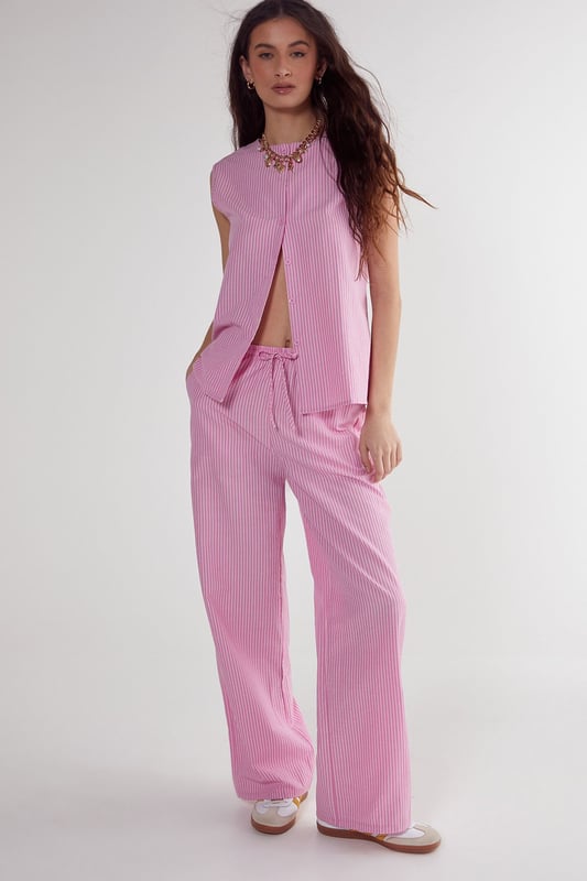 Straight leg design for a classic silhouette
        Vertical stripe pattern adds visual interest
        High-waisted fit for a flattering look
        Side pockets for practicality
        Coordinating sleeveless top with unique front opening
    
    Make a statement with these eye-catching stripe straight leg trousers from NastyGal. The vertical stripe pattern elongates your figure, while the high-waisted design accentuates your curves. Pair with the matching sleeveless top for a coordinated ensemble that's perfect for casual outings or family gatherings. The straight leg cut offers versatility, allowing you to style with trainers for a laid-back look or dress up with heels for a more polished appearance. The side pockets add functionality to this fashionable piece. For a trendy twist, layer with a cropped jacket or oversized blazer. These trousers are a wardrobe essential that can be dressed up or down, making them ideal for various casual occasions throughout the year.