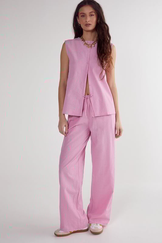 Straight leg design for a classic silhouette
        Vertical stripe pattern adds visual interest
        High-waisted fit for a flattering look
        Side pockets for practicality
        Coordinating sleeveless top with unique front opening
    
    Make a statement with these eye-catching stripe straight leg trousers from NastyGal. The vertical stripe pattern elongates your figure, while the high-waisted design accentuates your curves. Pair with the matching sleeveless top for a coordinated ensemble that's perfect for casual outings or family gatherings. The straight leg cut offers versatility, allowing you to style with trainers for a laid-back look or dress up with heels for a more polished appearance. The side pockets add functionality to this fashionable piece. For a trendy twist, layer with a cropped jacket or oversized blazer. These trousers are a wardrobe essential that can be dressed up or down, making them ideal for various casual occasions throughout the year.