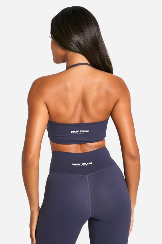 Stylish twist-front design for a unique look
        Halter neck style with racerback for enhanced support
        Soft, stretchy fabric for maximum comfort
        Medium support suitable for various activities
        Coordinating high-waisted leggings available for a complete set
    
    Elevate your workout wardrobe with this Dsgn Studio sports bra, perfect for the fashion-forward fitness enthusiast. The eye-catching twist-front detail adds a touch of style to your gym look, while the halter neck and racerback design provide ample support for medium-impact activities. Pair it with the matching high-waisted leggings for a coordinated ensemble that transitions seamlessly from your workout to casual outings. Layer with a loose-fitting cardigan or hoodie for a trendy athleisure look that's ideal for running errands or meeting friends for a casual coffee. The versatile design makes this sports bra a must-have for yoga sessions, gym workouts, or even as a stylish crop top for summer festivals. With its blend of fashion and function, this Boohoo piece is sure to become a staple in your active and leisure wear collection.