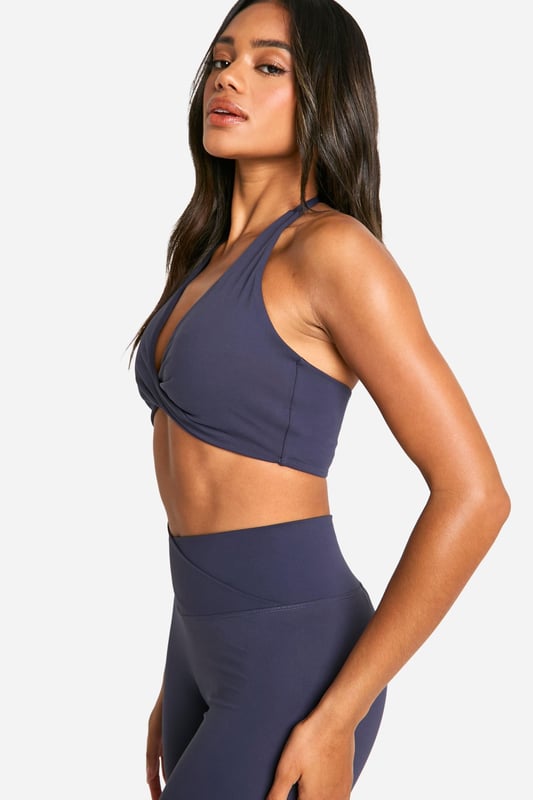 Stylish twist-front design for a unique look
        Halter neck style with racerback for enhanced support
        Soft, stretchy fabric for maximum comfort
        Medium support suitable for various activities
        Coordinating high-waisted leggings available for a complete set
    
    Elevate your workout wardrobe with this Dsgn Studio sports bra, perfect for the fashion-forward fitness enthusiast. The eye-catching twist-front detail adds a touch of style to your gym look, while the halter neck and racerback design provide ample support for medium-impact activities. Pair it with the matching high-waisted leggings for a coordinated ensemble that transitions seamlessly from your workout to casual outings. Layer with a loose-fitting cardigan or hoodie for a trendy athleisure look that's ideal for running errands or meeting friends for a casual coffee. The versatile design makes this sports bra a must-have for yoga sessions, gym workouts, or even as a stylish crop top for summer festivals. With its blend of fashion and function, this Boohoo piece is sure to become a staple in your active and leisure wear collection.