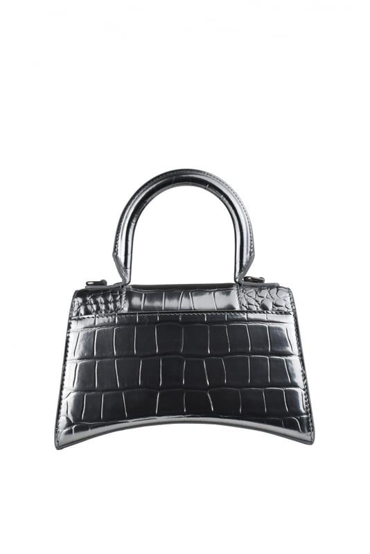 Bolso de mano Balenciaga Hourglass plateado.Piel de becerro grabada en cocodrilo.Placa con logotipo B de la firma en strass.Detalles metálicos plateados.Solapa superior con cierre de botón a presión.Asa redondeada.Bandolera extraíble y ajustable. Medidas: 19 cm x 12 cm x 8 cm.Talla pequeña.Made in Italy.
