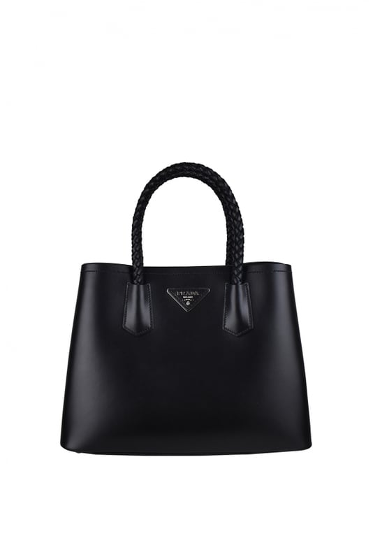 Bolso Double de Prada en suave piel negra.Icónico logotipo triangular plateado en la parte delantera del bolso.Doble asa de piel trenzada.Bandolera extraíble y ajustable.Detalles metálicos plateados.Cierre de botón de presión lateral.Dimensiones: 34 x 25 x 15 cm.100% piel.Made in Italy.