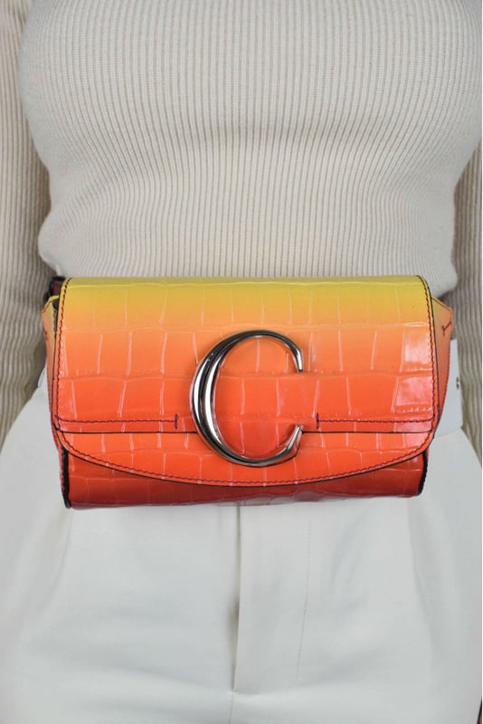 Riñonera Chloé C en piel con relieve de cocodrilo.Gradiente de amarillo y naranja.Solapa con botón magnético.Logotipo C plateado en la parte delantera.Cinturilla ajustable.Dimensiones del cinturón: largo mínimo 52 cm y máximo 62 cm.Dimensiones: ancho 17,5 cm, alto 11 cm, fondo 4 cm.Made in Italy.